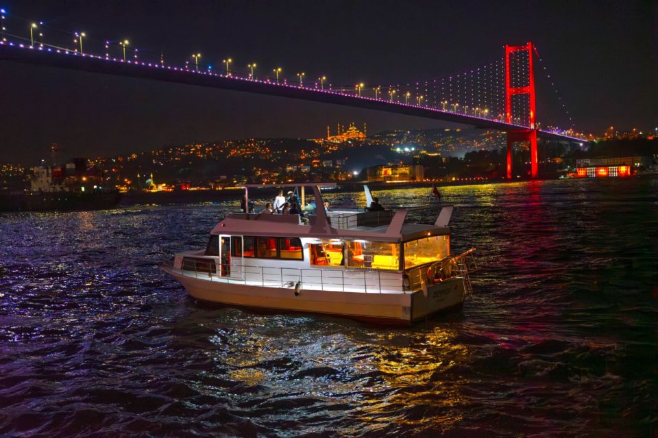 En cruisebåd sejler under den oplyste Bosphorus-bro i Istanbul om natten.