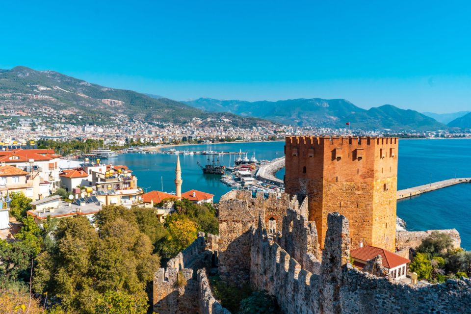Kizil Kule tower overlooks Alanya harbour with boats, the town and mountains behind.