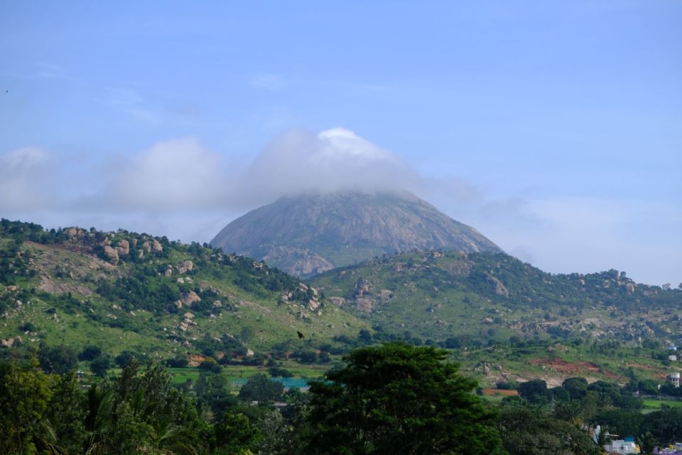 Nandi Hills in Karnataka rises as a cloud-capped peak above green, rocky slopes.