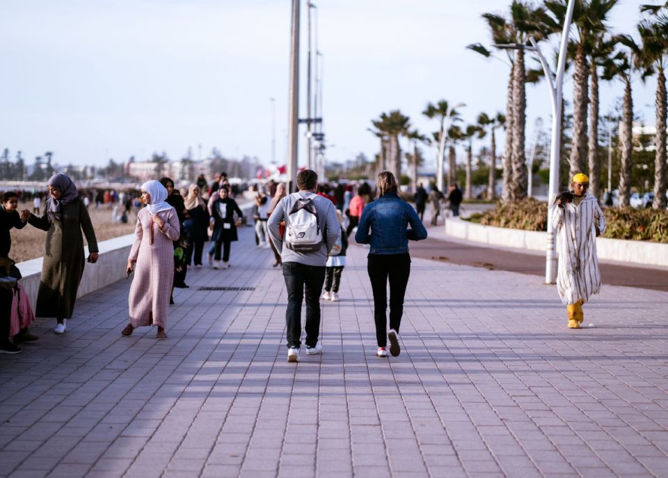 Ljudi šetaju promenadom pored mora u Agadiru tokom sunčanog dana.