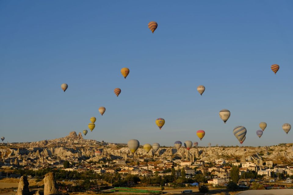Hot-air balloons rising over Göreme's rock formations and town in Cappadocia at sunrise