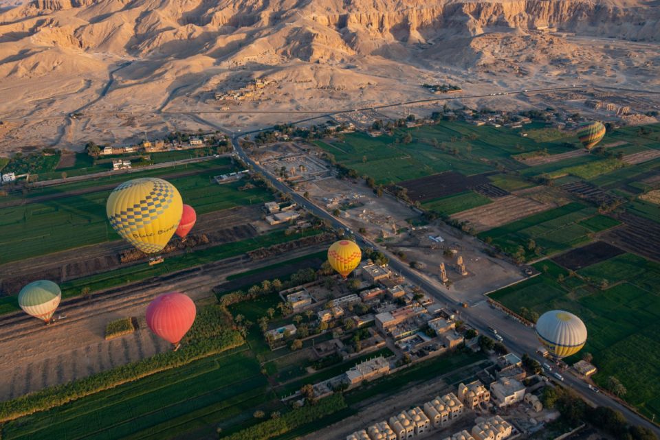 Hot air balloons drift over Luxor's fields and desert hills at sunrise