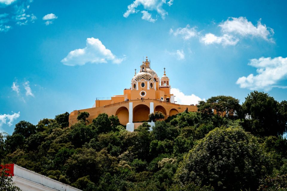 The Sanctuary of Our Lady of Remedies church atop the Great Pyramid of Cholula, under a blue sky.