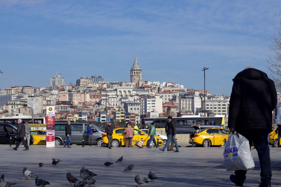 Yellow taxis line up near the waterfront in Istanbul with the Galata Tower visible across the water.