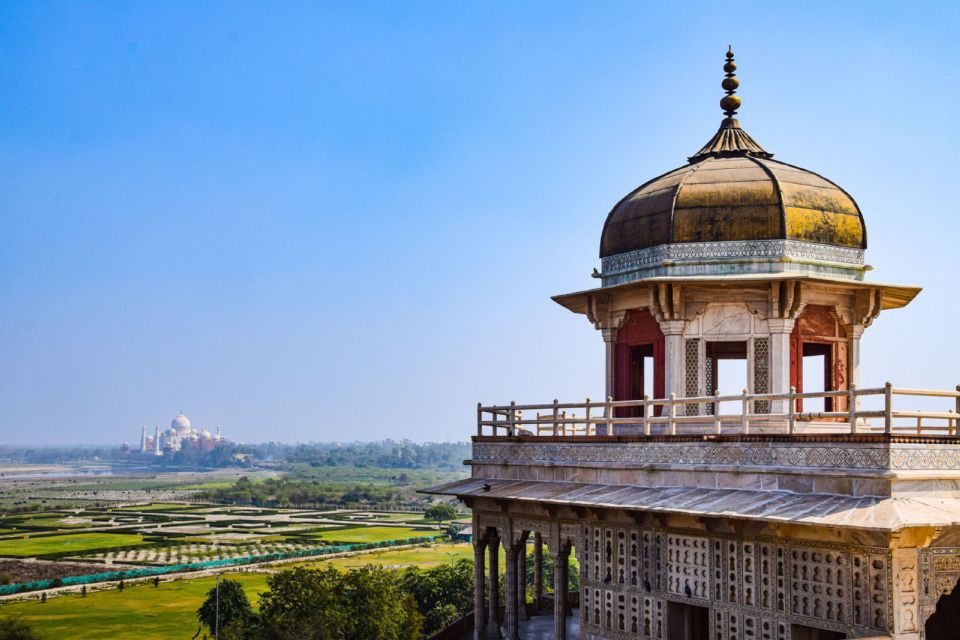 Agra Fort's domed pavilion overlooks farmland with the Taj Mahal visible in the distance.
